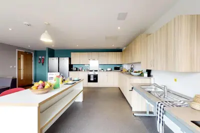 a large kitchen with white cabinets and blue walls at Abodus St James Glasgow in Glasgow