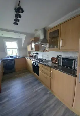 a kitchen with wooden cabinets and a stove top oven at Idyllic Waterside Penthouse in Callander