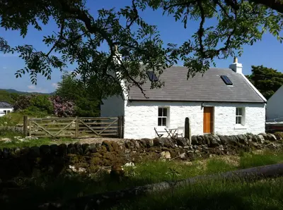 a white house with a fence in front of it at Cnocachanach Cottage in Tarbert
