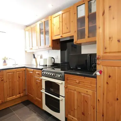 a kitchen with wooden cabinets and a stove top oven at Cnocachanach Cottage in Tarbert