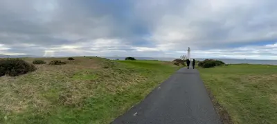 a person walking down a path with a lighthouse in the distance at Peel House Bed and Breakfast in Girvan