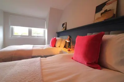a bedroom with two beds with red pillows at Signature - Martin House in Old Monkland