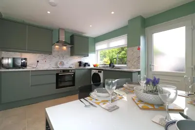 a kitchen with green cabinets and a table with wine glasses at Signature - Martin House in Old Monkland