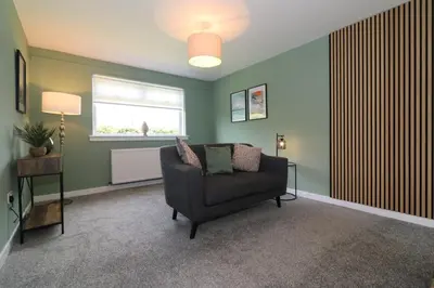 a living room with a chair and a window at Signature - Martin House in Old Monkland