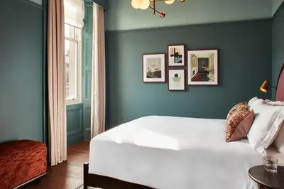 a bedroom with a white bed and a blue wall at The Hoxton, Edinburgh in Edinburgh