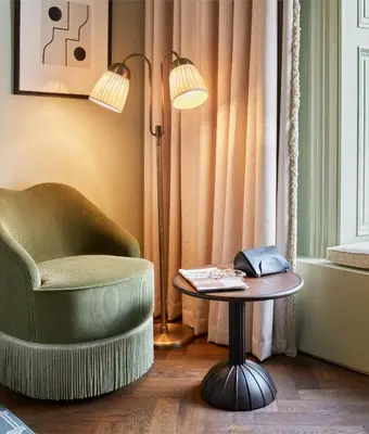 a room with a chair and a table and a lamp at The Hoxton, Edinburgh in Edinburgh
