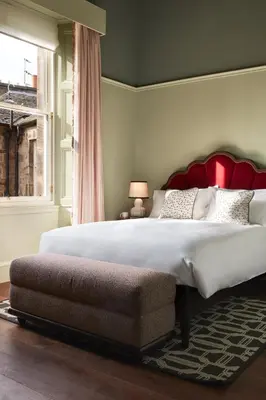 a bedroom with a large bed with a red headboard at The Hoxton, Edinburgh in Edinburgh
