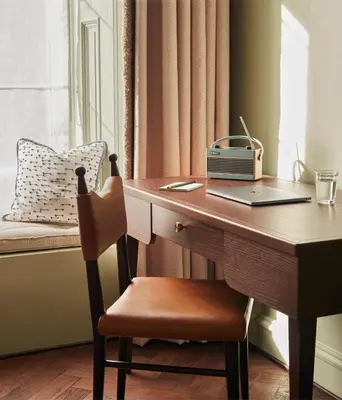 a desk with a laptop and a chair next to a window at The Hoxton, Edinburgh in Edinburgh