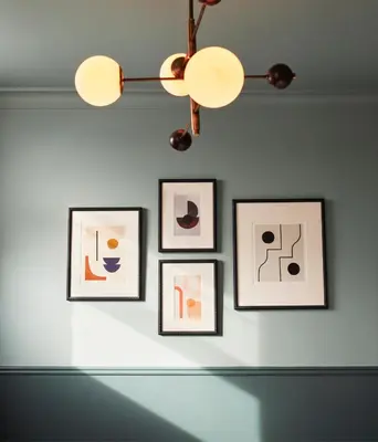 a group of pictures on a wall with a chandelier at The Hoxton, Edinburgh in Edinburgh