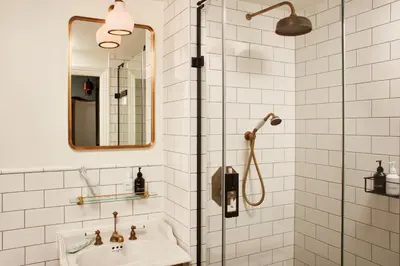 a bathroom with a shower with a sink and a mirror at The Hoxton, Edinburgh in Edinburgh