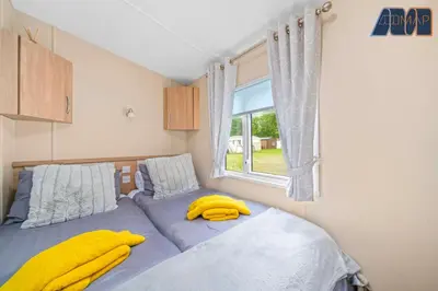 a bedroom with a bed with yellow towels on it at Loch Lomond - Ard Lui Lodge in Ardlui