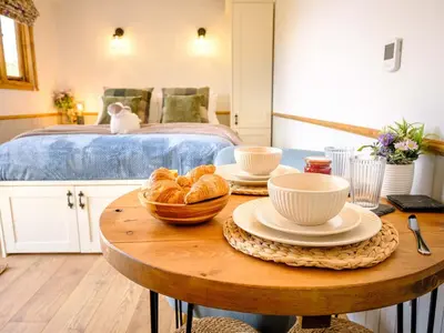 a room with a table with croissants and a bed at Lintmill Lodges - Bluebell Shepherds Hut in Sorn