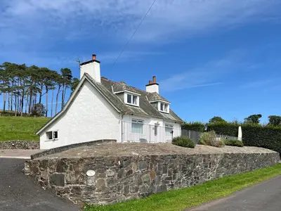 a white house sitting on top of a stone wall at Balnowlart Lodge in Ballantrae