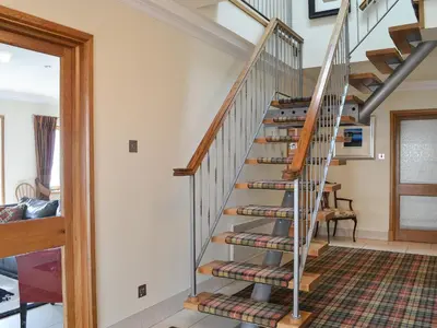 a spiral staircase in a home with wooden railings at Waterside in Tighnabruaich