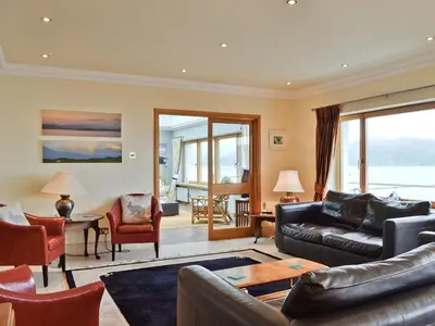 a living room with a leather couch and chairs at Waterside in Tighnabruaich