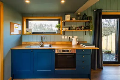 a kitchen with blue cabinets and a sink and a window at Jura - The Rusty Hut in Craighouse