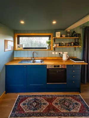 a kitchen with blue cabinets and a sink at Jura - The Rusty Hut in Craighouse