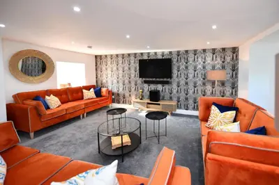 a living room with orange couches and a tv at 20 The Courtyard, Ballochmyle House in Mauchline