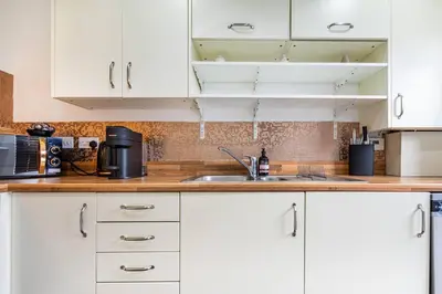 a kitchen with white cabinets and a sink at Bright, modern 2 bedroom house with free parking! in Edinburgh