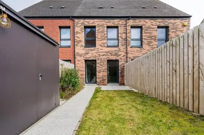 a brick house with a fence in front of it at Bright, modern 2 bedroom house with free parking! in Edinburgh