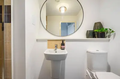 a white bathroom with a sink and a mirror at Bright, modern 2 bedroom house with free parking! in Edinburgh
