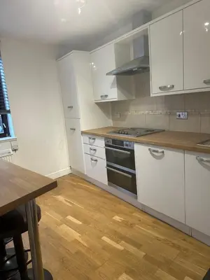 a kitchen with white cabinets and a wooden floor at Edinburgh Lauriston 4 bedroom 7 beds duplex in Edinburgh