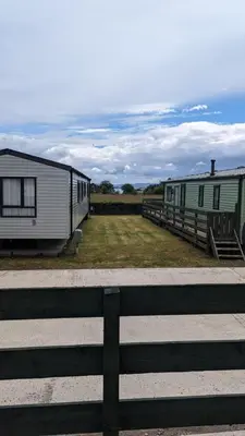 two mobile homes are parked next to a fence at The Brockenhurst 25 in Dunoon
