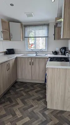 an empty kitchen with wooden cabinets and a window at The Brockenhurst 25 in Dunoon