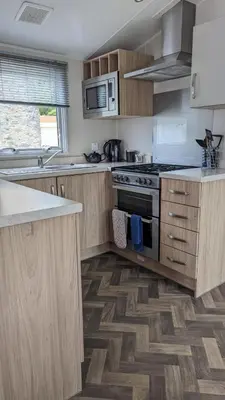 a kitchen with wooden cabinets and stainless steel appliances at The Brockenhurst 25 in Dunoon