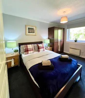 a bedroom with a large bed with two towels on it at Spacious 2 Bed-Flat in Glasgow City - Free Parking in Glasgow