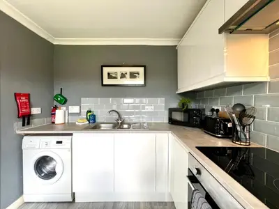 a kitchen with white cabinets and a washer and dryer at Spacious 2 Bed-Flat in Glasgow City - Free Parking in Glasgow