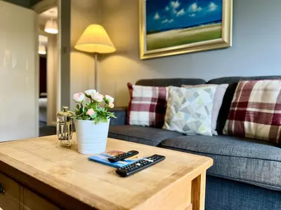 a coffee table with two remote controls and a couch at Spacious 2 Bed-Flat in Glasgow City - Free Parking in Glasgow