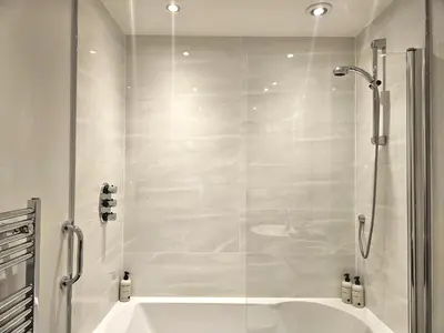 a white bathroom with a shower and a tub at Edinburgh Elegant 1-Bedroom City Apartment in Edinburgh