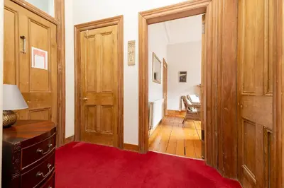 a hallway with wooden doors and a red rug at Charming 1-Bedroom Edinburgh City Getaway in Edinburgh