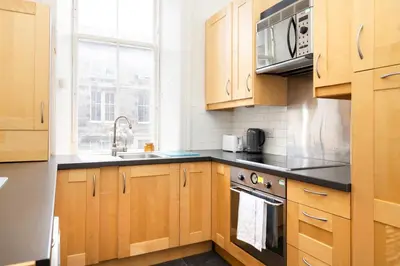 a kitchen with wooden cabinets and a sink at Charming 1-Bedroom Edinburgh City Getaway in Edinburgh