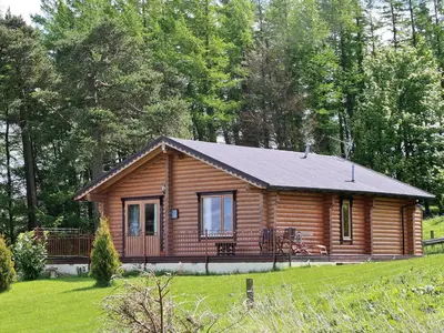 a log cabin with a porch in a field at Fingask Log Cabin - S4394 in Glenfarg