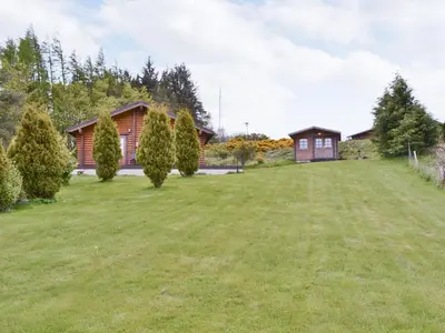 a large lawn in front of a house at Fingask Log Cabin - S4394 in Glenfarg