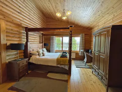 a bedroom with a bed in a wooden cabin at Bracken Log Cabin - S4468 in Glenfarg