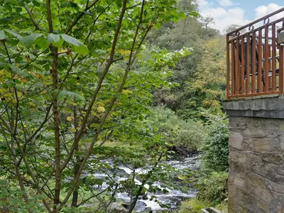 a bridge over a river next to a forest at The Wheelhouse in Linlithgow