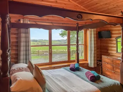 a bedroom with a bed with a large window at Ashknowe Log Cabin - S4590 in Glenfarg