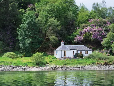 a small white house on the shore of a river at Shore Cottage - S4600 in Tarbert