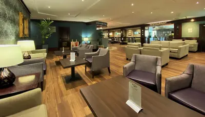 a waiting room with couches and tables and chairs at Normandy Hotel (Near Glasgow Airport) in Paisley