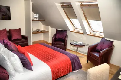 a bedroom with two chairs and a bed at Glynhill Hotel & Spa near Glasgow Airport in Paisley