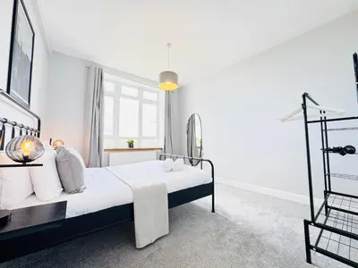 a white bedroom with a bed and a window at Skyline View Apartment in Edinburgh