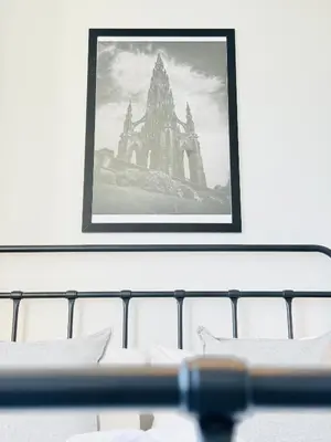 a picture hanging on a wall above a table with pillows at Skyline View Apartment in Edinburgh