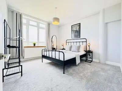 a white bedroom with a bed and a window at Skyline View Apartment in Edinburgh