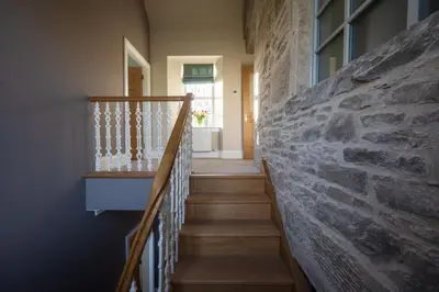a staircase in a house with a stone wall at Milton House in Buchanty