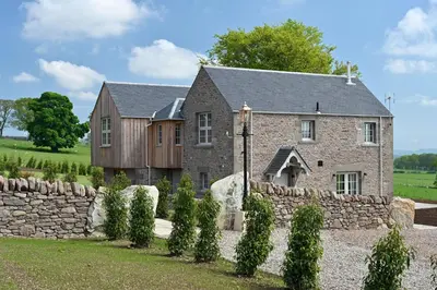 a large stone house with a stone wall at The Old Farmhouse in Buchanty