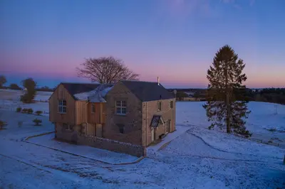 a house in a field with snow on the ground at The Old Farmhouse in Buchanty