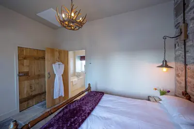 a bedroom with a bed and a dress hanging on a wall at Falcon Steading in Buchanty